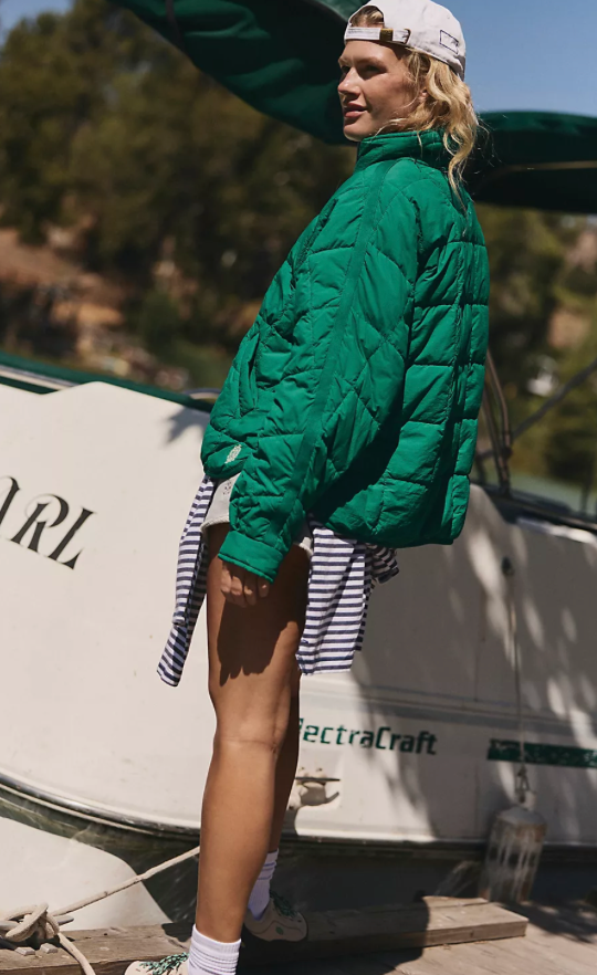 Person wearing FP Movement green puffer jacket standing next to a boat.